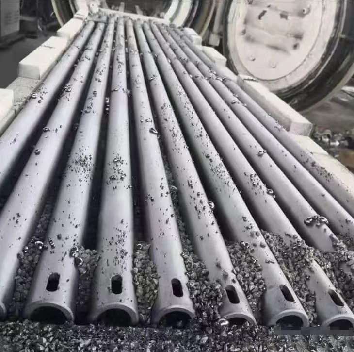 Ceramic tubes arranged on a loading bed beside an open furnace