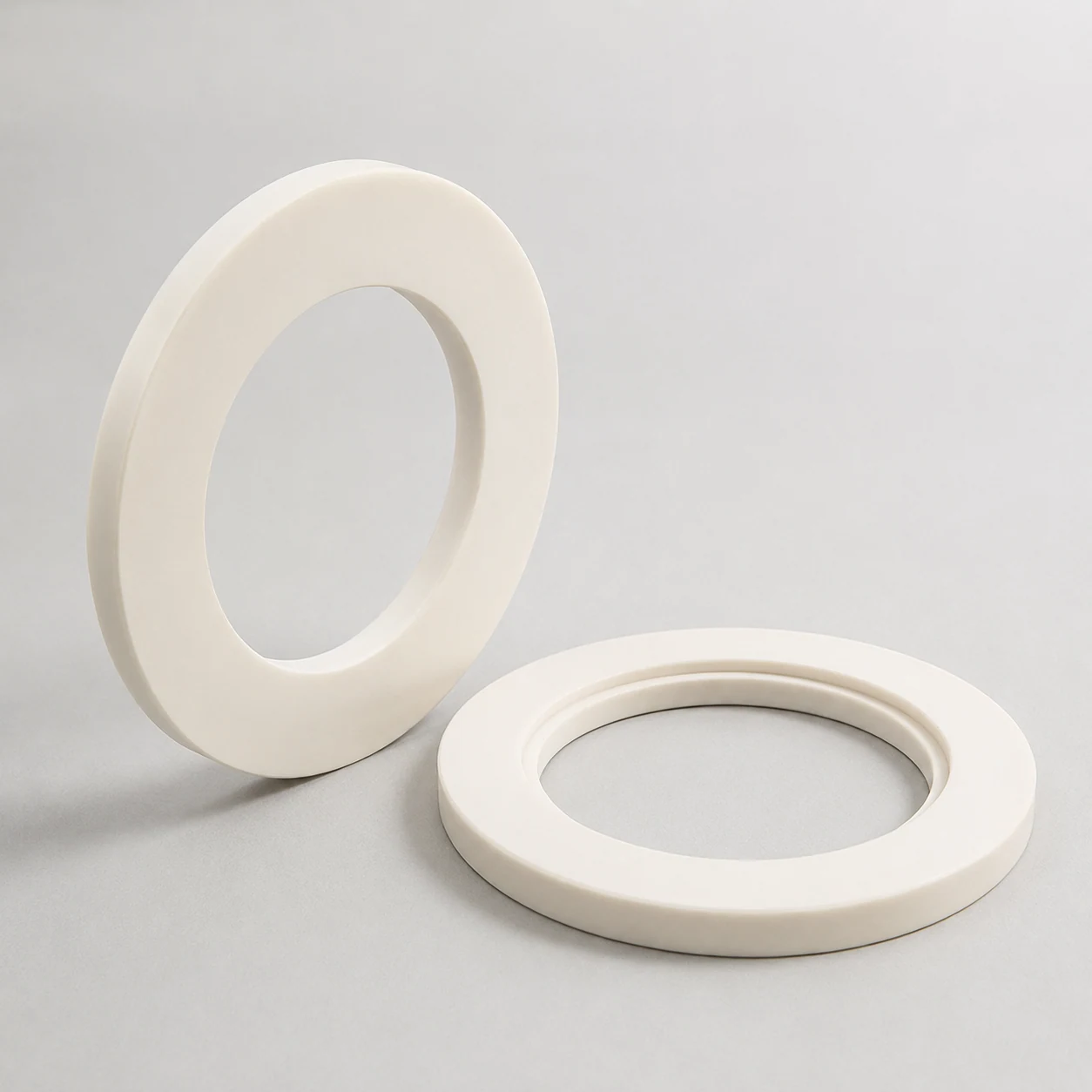 Two alumina ceramic insulating rings in upright and flat views