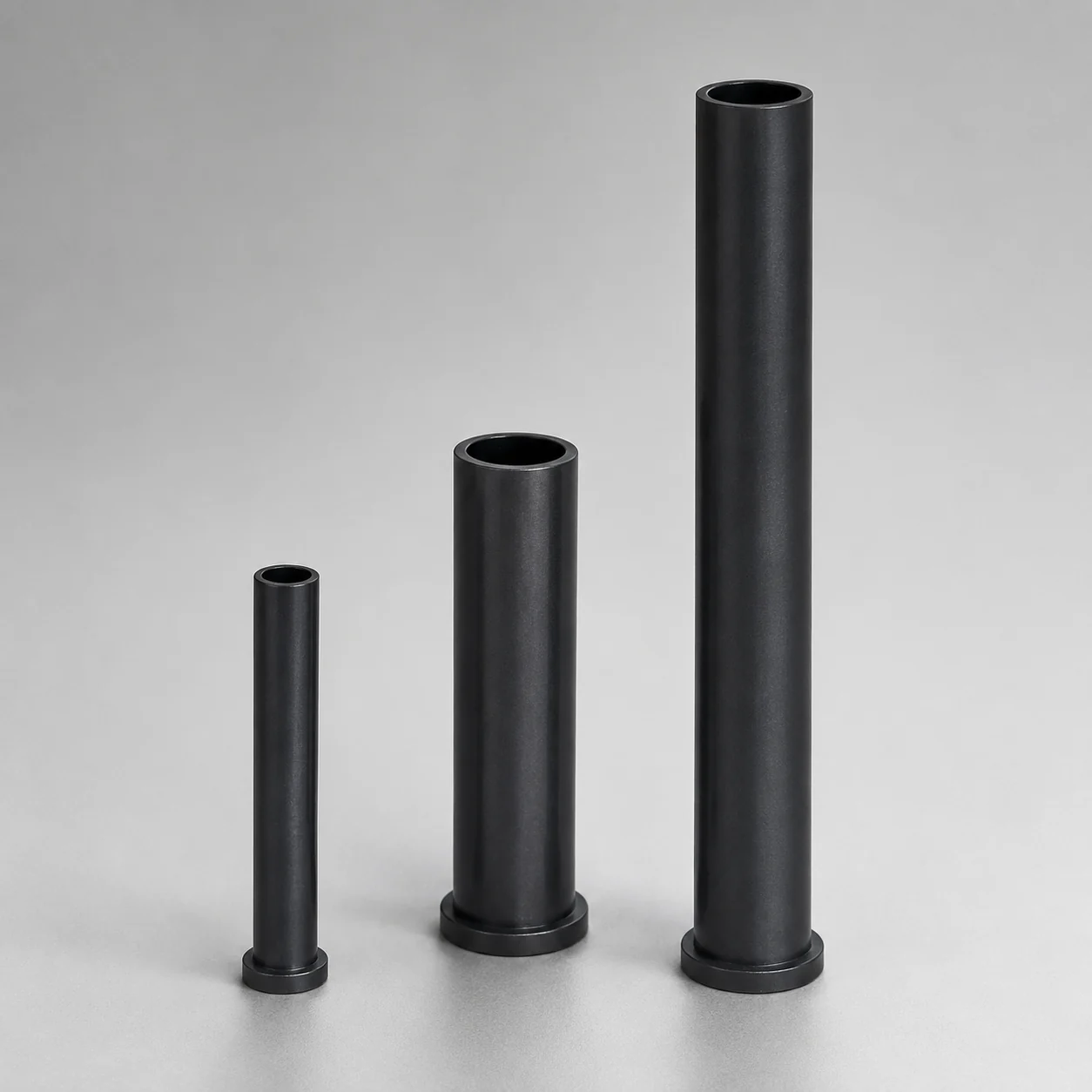 Three silicon nitride riser tubes with flanged bases in different sizes